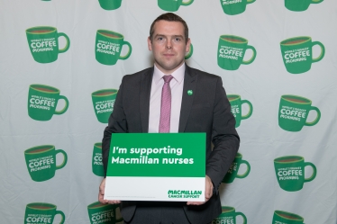 Douglas holds Macmillan Cancer charity poster